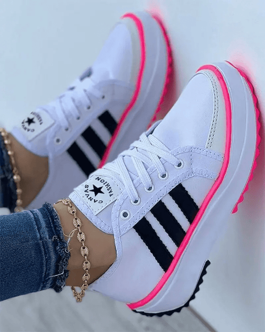 White sneakers with black stripes and pink soles worn by a person.